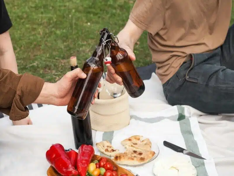 duas pessoas brindando com dois growler de cerveja