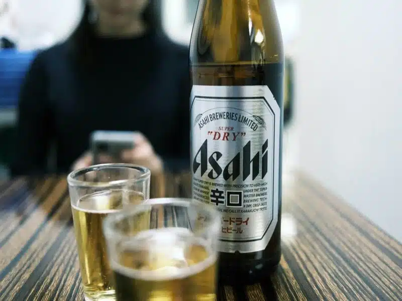 uma das marcas de cerveja asahi super dry com dois copos de vidro ao lado
