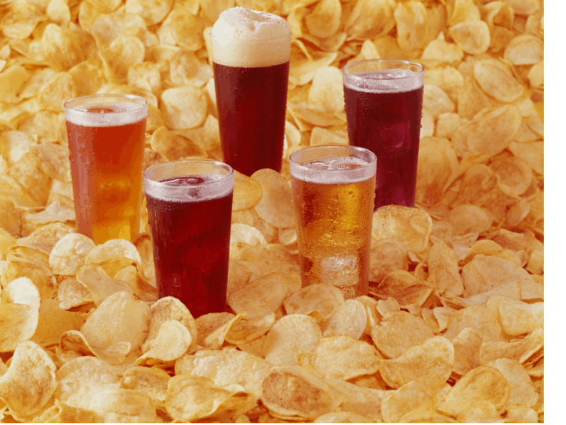 A imagem apresenta cinco copos de cerveja de diferentes tipos dispostos sobre uma cama de batatas fritas crocantes. A cerveja parece variar em cor, com algumas sendo mais douradas e outras mais escuras, sugerindo uma variedade de estilos, como uma cerveja clara e uma mais escura, possivelmente uma stout ou uma ale.