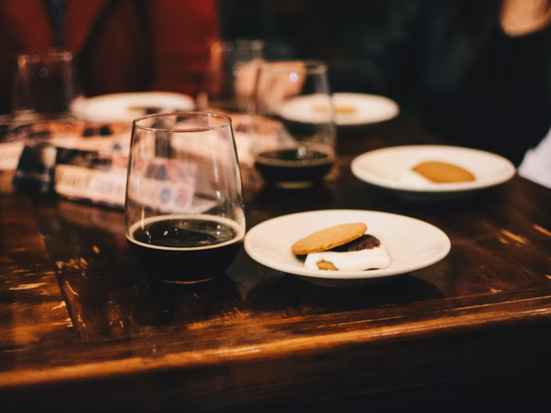 A imagem mostra uma mesa de madeira escura com pratos pequenos contendo biscoitos com marshmallow e chocolate