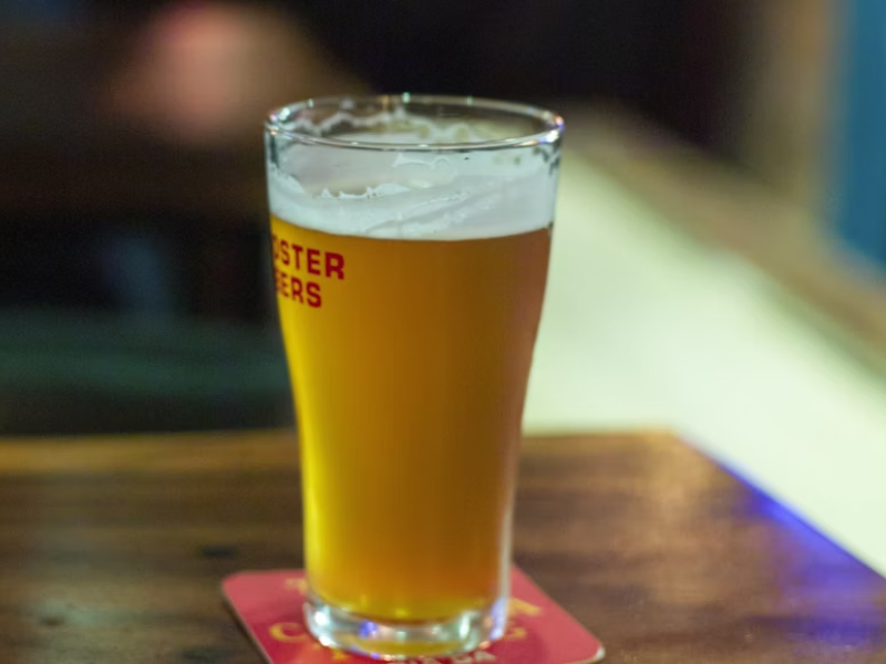 A imagem mostra um copo de cerveja do tipo pint, com a coloração amarela turva, indicando que provavelmente se trata de um estilo como Hefeweizen, Witbier ou uma New England IPA (NEIPA) — estilos conhecidos por sua aparência não filtrada e opaca devido a um dos tipos de malte.